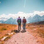 two person walking on unpaved road